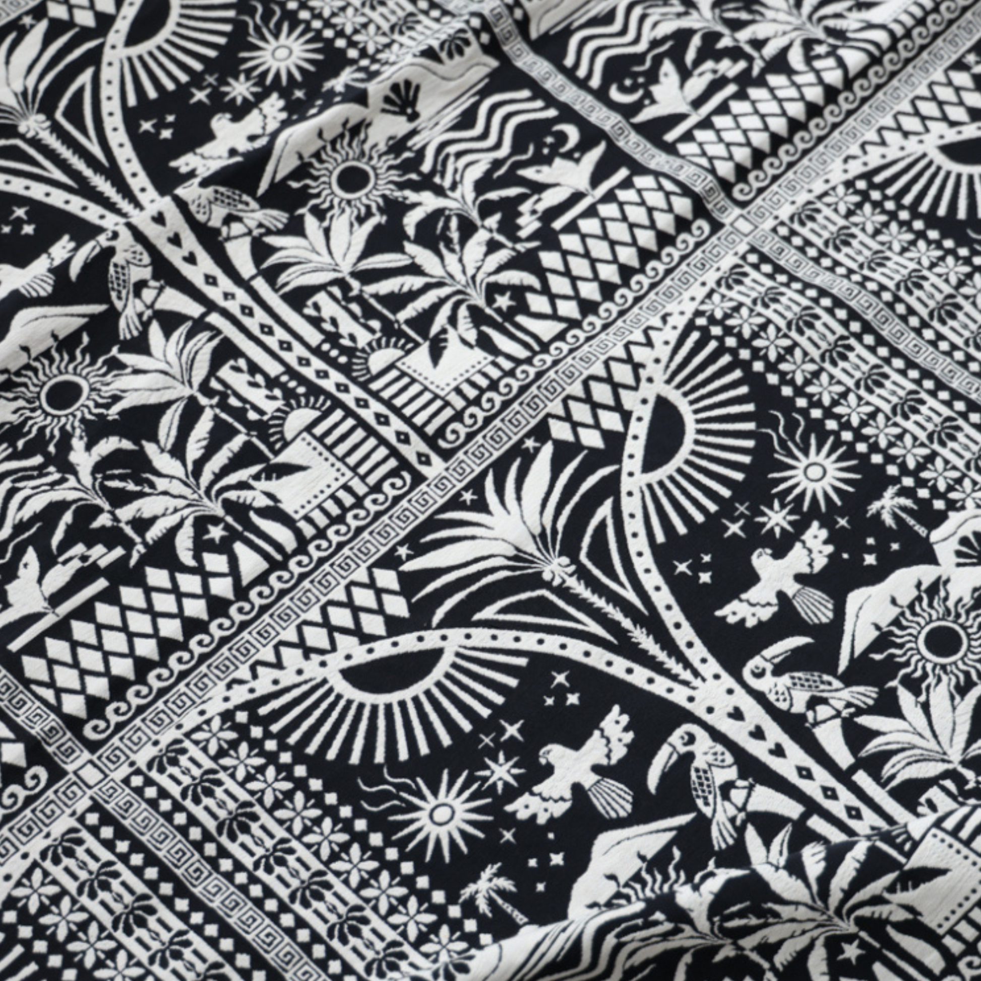 Close up of black and white fabric. features intricate designs, including geometric shapes, birds, and plants, with two front pockets that match the detailed print. The bold design gives the vest a unique, handcrafted look.